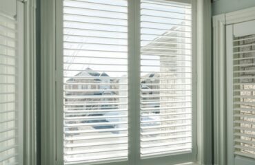 timeless-shutters-designed-for-modern-living A window with interior shutters and a cozy window seat beneath it, inviting natural light into the room.