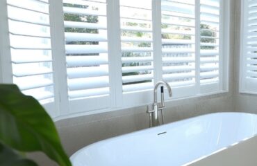 bespoke-shutters-to-suit-your-space A bathroom featuring white interior shutters and a spacious bathtub, creating a bright and airy atmosphere.