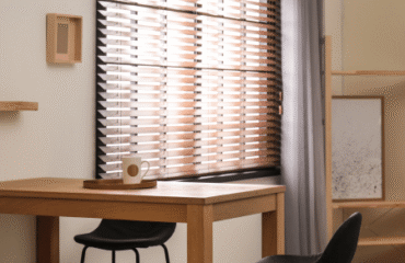 enhance-your-home-with-combi-panel-shutters A table with a chair beside it, featuring combi panel blinds in the background.